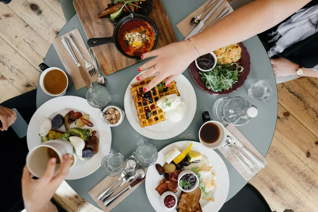 Overhead view of friends sharing brunch plates and coffee at a round table